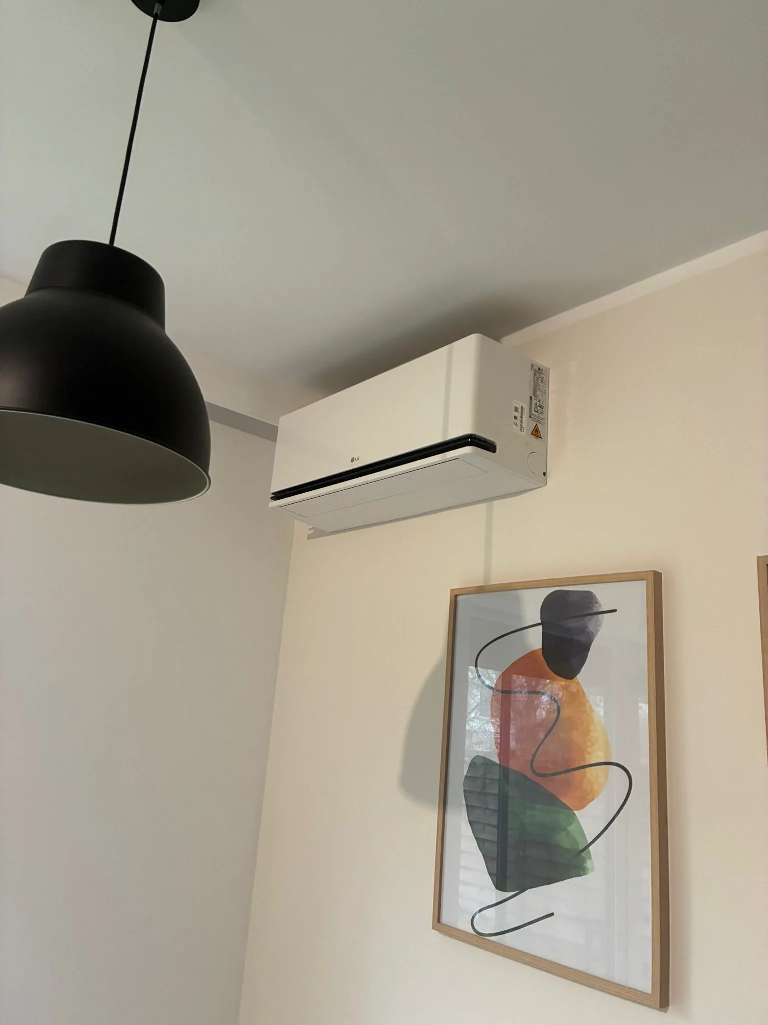 Ścienny klimatyzator split zamontowany nad abstrakcyjnym obrazem w eleganckim wnętrzu