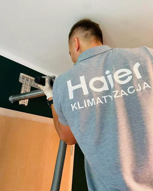 Monter instalujący klimatyzator split na stalowym wsporniku pod sufitem