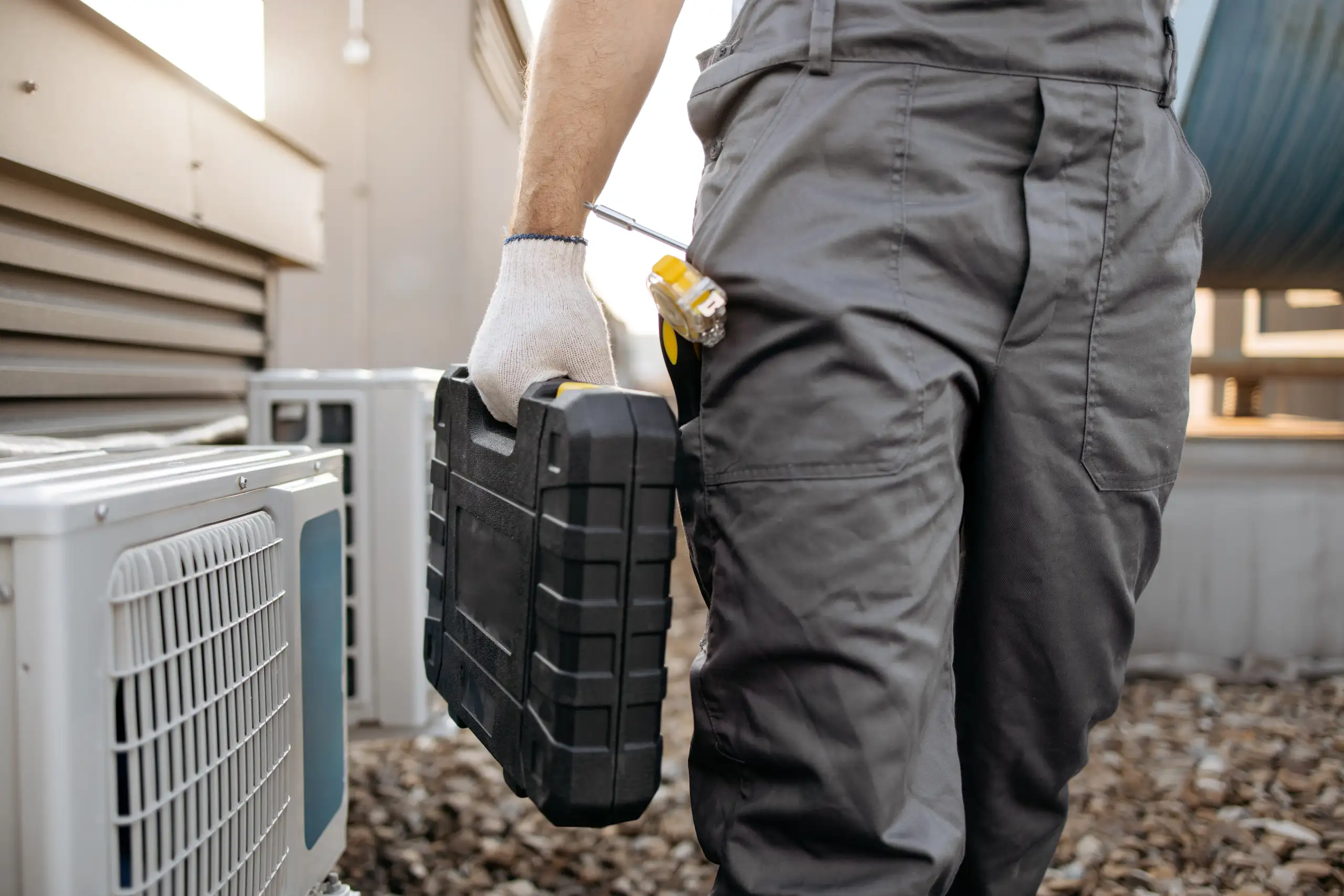 Technik serwisu klimatyzacji z walizką narzędziową przy zewnętrznym agregacie Serwis klimatyzacji