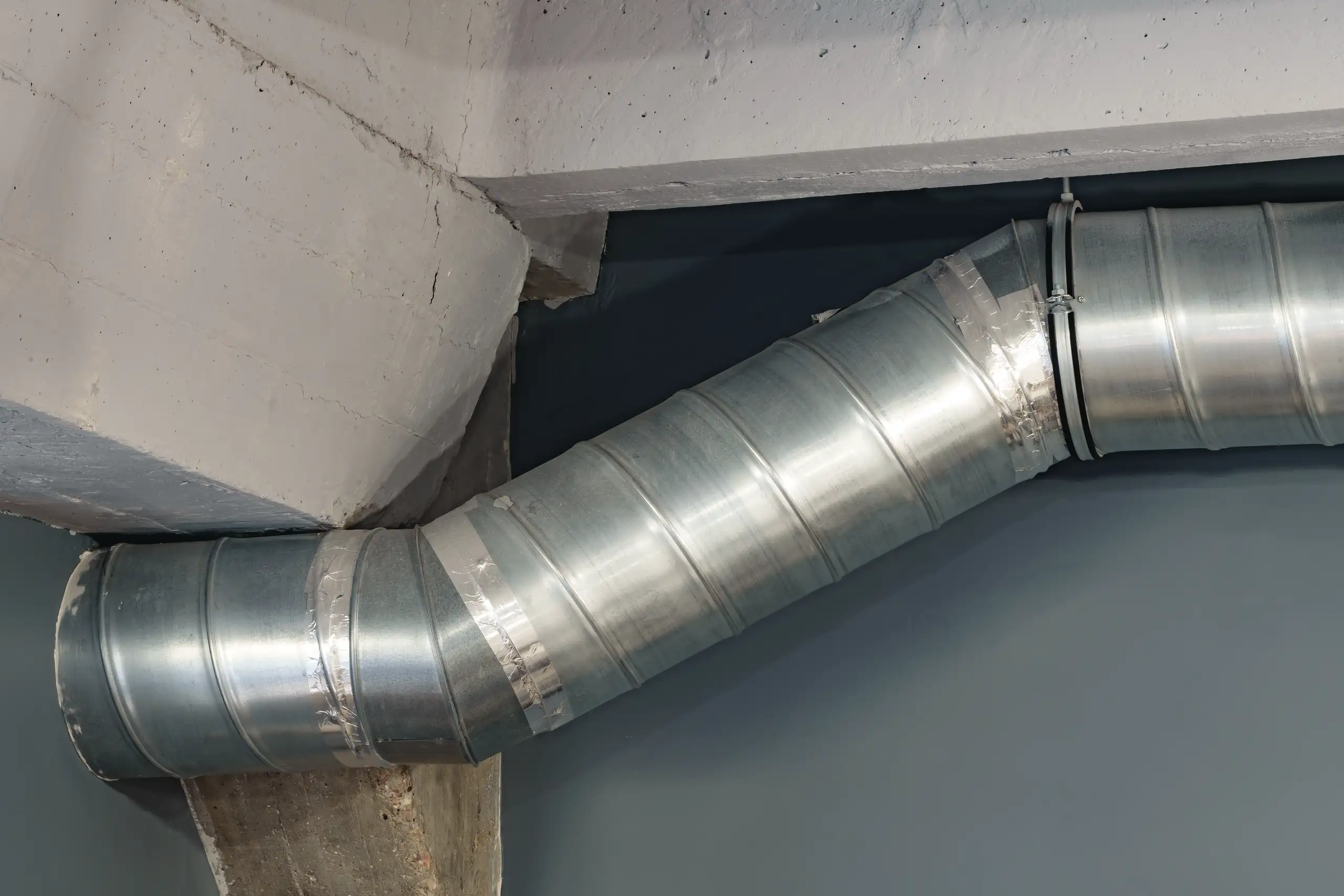 Spiralny metalowy kanał przy sufitowej belce betonowej - instalacja wentylacji mechanicznej