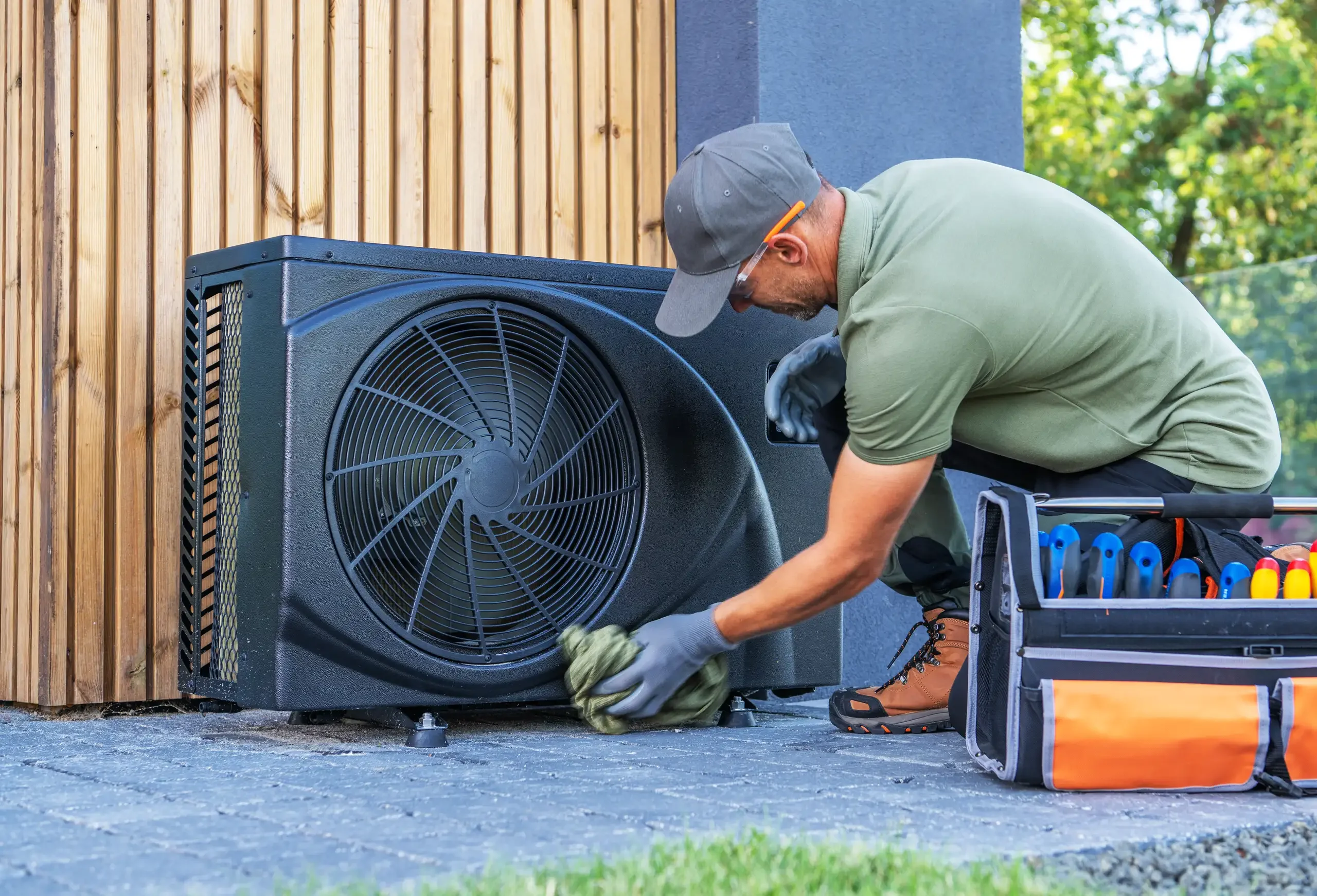 Czyszczenie klimatyzacji – technik czyści zewnętrzną jednostkę split przy elewacji domu